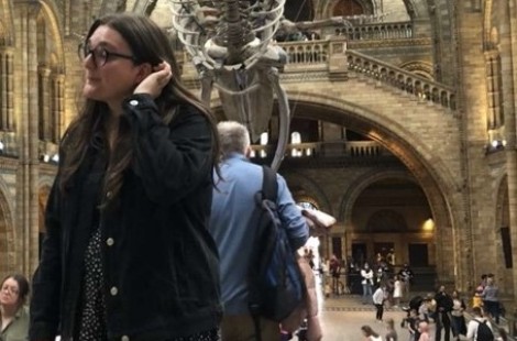 A candid photo of Olivia in the Natural History Museum in London. Behind her is the foyer with the museum's famous skeleton of a blue whale suspended from the ceiling.
